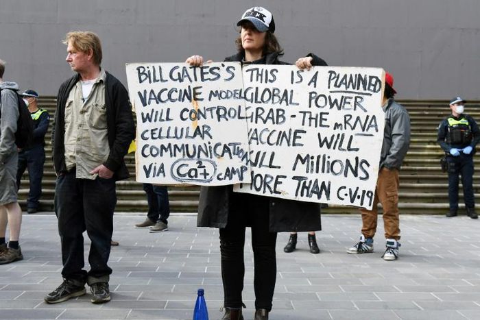An anti-lockdown protester holds placards on the steps of Victoria's state parliament in Melbourne