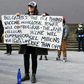 An anti-lockdown protester holds placards on the steps of Victoria's state parliament in Melbourne