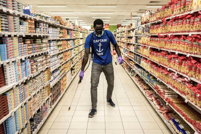 A man disinfects an empty supermarket in Dakar