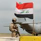 An Iraqi soldier stands guard in front of a US military air carrier at the Qayyarah air base, near Mosul in northern Iraq, on March 26, 2020. The US says it will reduce troops in the country "over coming months"