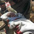 An Afghan security officer carries a newborn baby from a hospital after it is attacked in Kabul