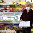 Shop owner Mudaver Uygur shows the book where he notes money owed him by costumers -- wealthier ones have stepped into the breach to pay off debts worth hundreds of dollars in some cases