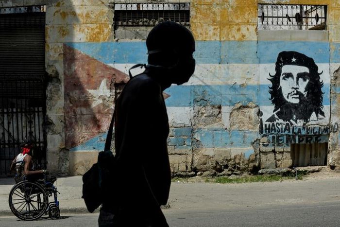 A Cuban man wears a face mask in front of a mural showing revolutionary Che Guevara in Havana -- the coronavirus cases are limited here, but food shortages have become worse as a result of the crisis