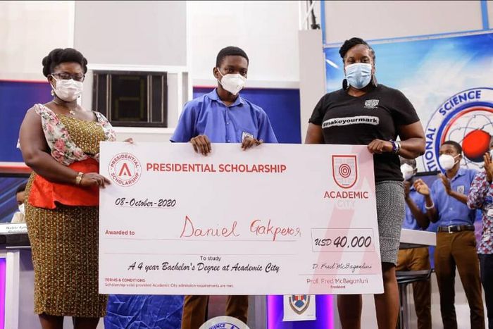 Dr Lucy Agyepong (right) and Ms Shannan Akosua Magee of Academic City presenting the scholarship to Mr Daniel Kekeli Gakpetor (middle)