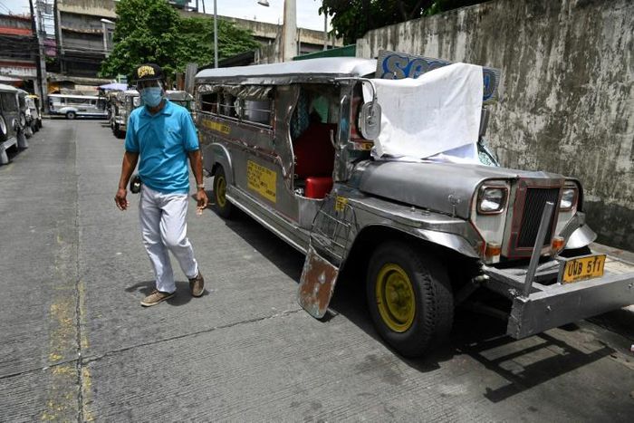 A resident walks past jeepneys serving as temporary homes parked along a road in Manila