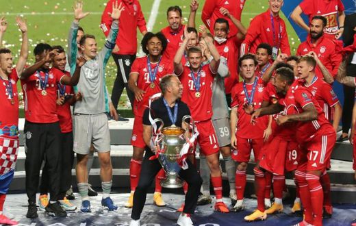 Bayern Munich players and coach Hansi Flick celebrate with the trophy after beating PSG in Sunday's Champions League final in Lisbon