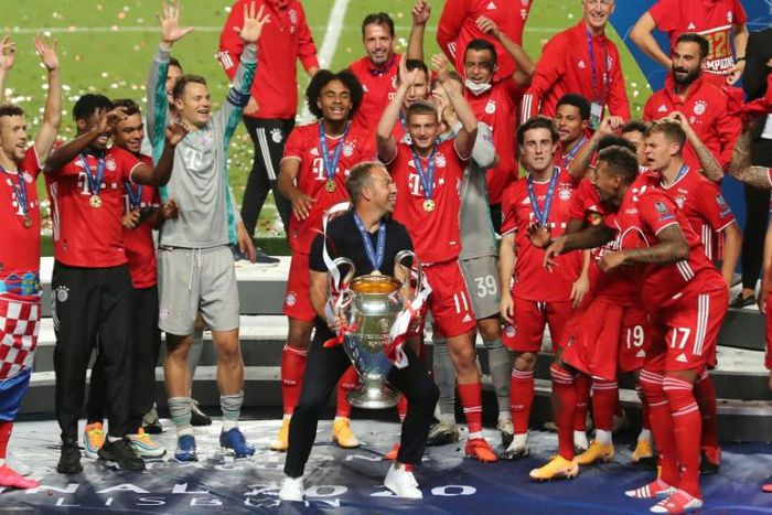 Bayern Munich players and coach Hansi Flick celebrate with the trophy after beating PSG in Sunday's Champions League final in Lisbon