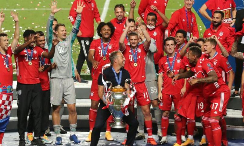 Bayern Munich players and coach Hansi Flick celebrate with the trophy after beating PSG in Sunday's Champions League final in Lisbon