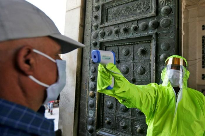 A medic outside Damascus's Umayyad Mosque checks the temperatures of worshippers before they are allowed to enter