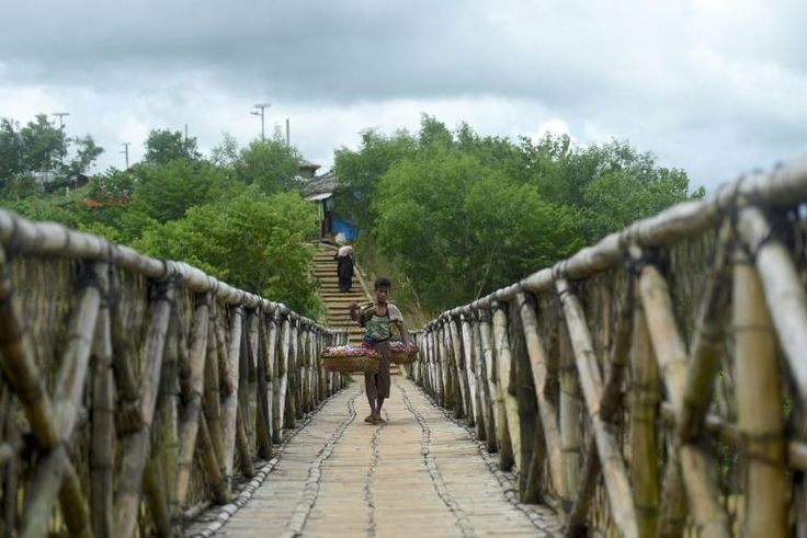A Rohingya worker walks across a bamboo bridge in Kutupalong refugee camp in Ukhia, Bangladesh