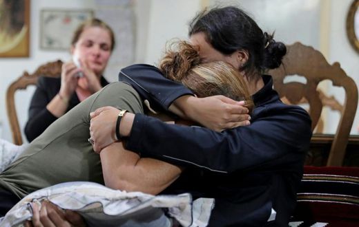 (L to R) Rita Hitti (mother of 27-year-old missing fireman Najib) and her daughter Carlyn (wife of 37-year-old missing fireman Charbel Karam) cry as they comfort each other at their home in the mountain town of Qartaba, north of the Lebanese capital
