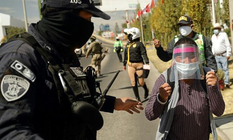 A policeman blocks Celia Capira as she tries to approach Peru's President Martin Vizcarra to plead for help in saving her husband's life as he struggles with coronavirus