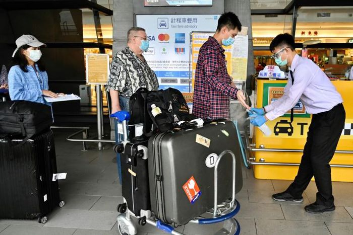 A worker sprays sprays hand sanitizer onto passengers arriving in March 2020 at Taoyuan Airport in Taiwan, one of the few places for which the United States has completely lifted its warning to avoid travel due to the coronavirus