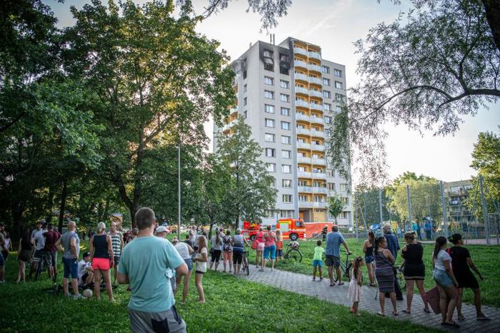 People look on as firefighters work at the scene where a fire broke out in an apartment block in Bohumin, eastern Czech Republic on August 8, 2020, killing eleven people including three children