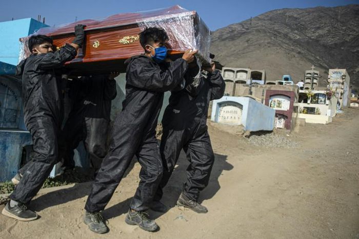 Cemetery workers carry the coffin of a COVID-19 victim at a graveyard in Comas, in the northern outskirts of Lima