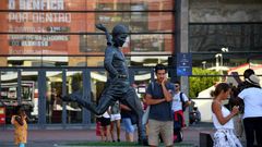 Football fans take pictures next to the statue of Portugal legend Eusebio outside Benfica's Estadio da Luz, which will host the Champions League final on August 23