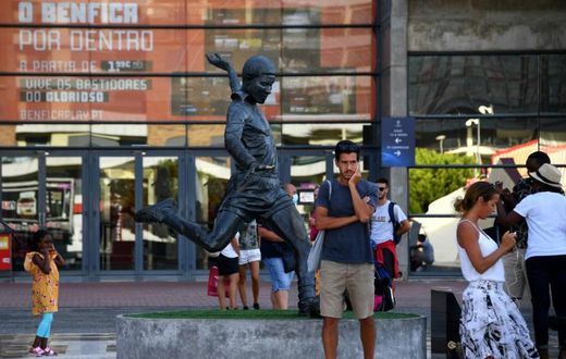 Football fans take pictures next to the statue of Portugal legend Eusebio outside Benfica's Estadio da Luz, which will host the Champions League final on August 23