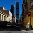 A nun wearing a facemask pushes a trolley in the outskirts of Madrid with the Cuatro Torres business area in the background