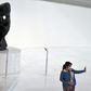 A visitor -- wearing a face mask -- takes a selfie at the Soumaya Museum in Mexico City in front of a Rodin sculpture