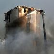 Lebanese firefighters use a ladder to hose down the warehouses and silos of Beirut port after Thursday's blaze