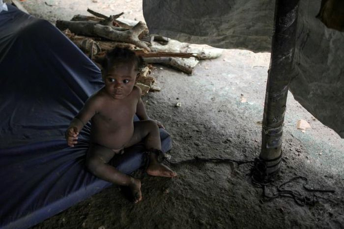A baby is tied to a post to keep her from crawling away at the migrant camp in La Penita, Panama, which is home to around 1,500 migrants