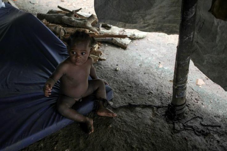A baby is tied to a post to keep her from crawling away at the migrant camp in La Penita, Panama, which is home to around 1,500 migrants