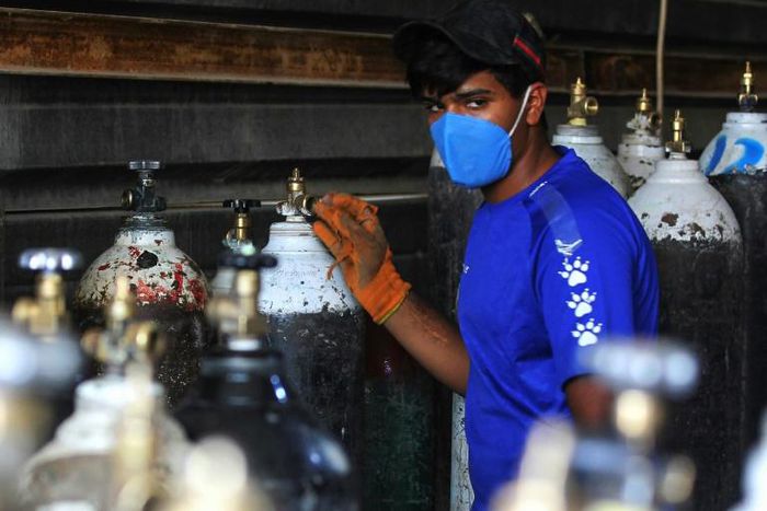 A worker refills oxygen cylinders at a factory in Taji district north of Iraq's capital Baghdad, before delivering them to hospitals amid the COVID-19 pandemic