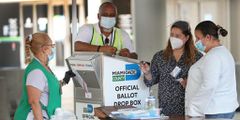 Poll workers in Miami helping a voter use an official Miami-Dade County ballot drop box on August 11.