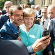 An asylum seeker takes a selfie with German Chancellor Angela Merkel, in Berlin on September 10, 2015 at the beginning of Europe's migrant crisis