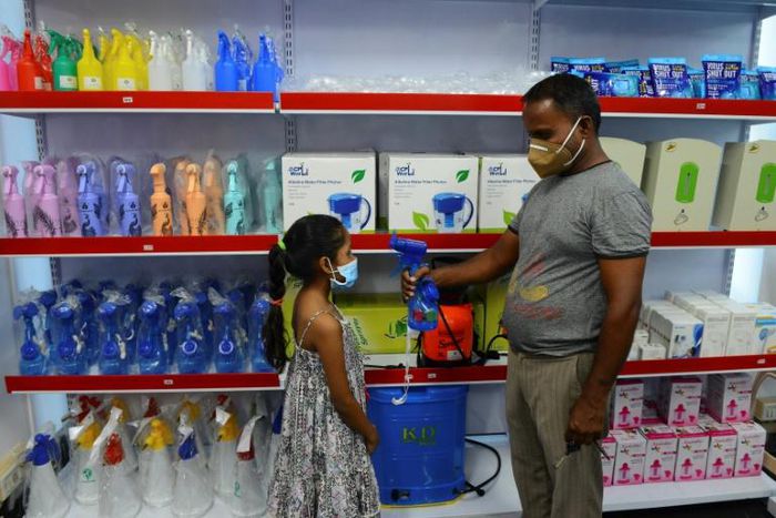 A storekeeper shows to a child a fan-sprinkler used for spraying disinfectant, at a shop selling products against the spread of Covid-19 in Vallabh Vidyanagar, 65km from Ahmedabad, India