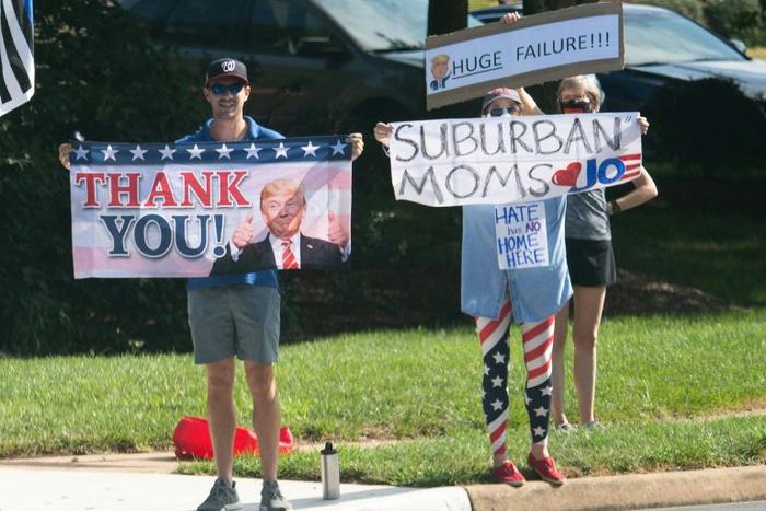Supporters of Donald Trump and Joe Biden wave competing signs as the president's convoy arrives at a golf course in Sterling, Virginia, on August 23, 2020