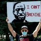 A demonstrator holds up a poster with a rendition of George Floyd on May 30 in Denver
