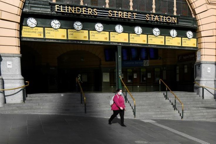 A woman walks out of a near-deserted Flinders Street Station in Melbourne after the state announced new restrictions to contain coronavirus