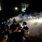 Protesters run as police shoot teargas in an effort to disperse demonstrations against the shooting of Jacob Blake in Kenosha, Wisconsin on August 25, 2020, with Facebook saying it has removed accounts linked to the violence
