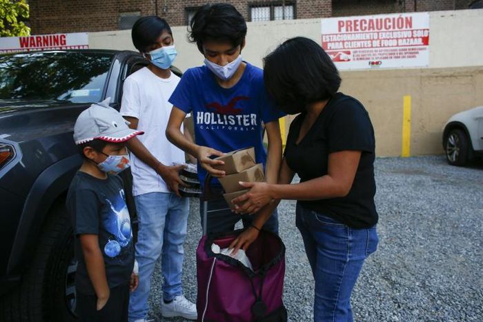 Maria, a domestic worker from Mexico, and her children receive food donations at a distribution center in Corona, Queens