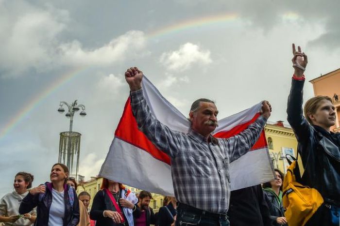 A man holds a historical Belarus flag atan opposition rally in Minsk -- growing protests against President Lukashenko and resulting uncertainty have sent the local currency tumbling