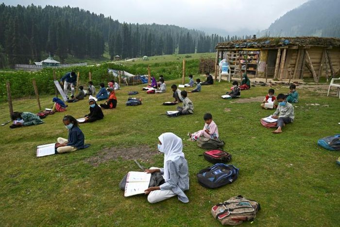 Students attend an open-air school in a highland meadow in in Doodhpathri, Indian-administered Kashmir