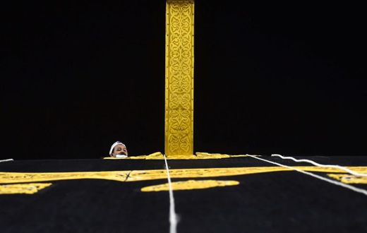 A Saudi workman adjusts the new kiswa, the gold-embroidered black cloth covering the Kaaba, that is changed during each year's hajj