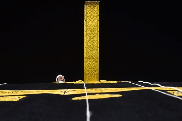 A Saudi workman adjusts the new kiswa, the gold-embroidered black cloth covering the Kaaba, that is changed during each year's hajj
