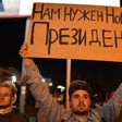 A man holds a poster reading "We need a new president" during a protest rally against police violence