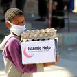 A child wearing a protective mask receives humanitarian aid in Yemen's third city of Taez, on May 8, 2020, amid the coronavirus pandemic