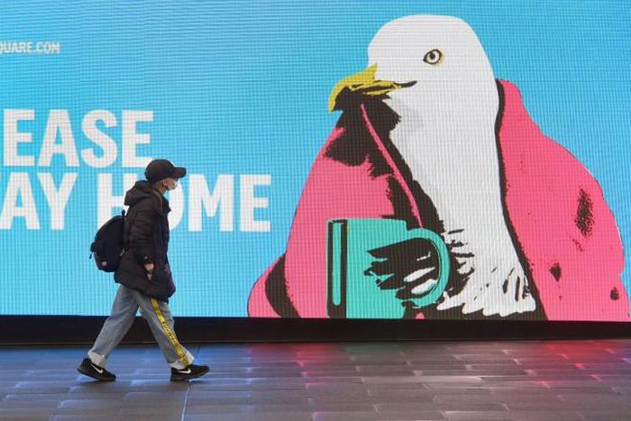 A woman walks past a sign urging people to stay home in Melbourne, which is under lockdown as the city battles an outbreak of the coronavirus