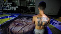 A supporter of Diego Maradona, kneels outside the private clinic where Argentine former football star underwent brain surgery for a blood clot