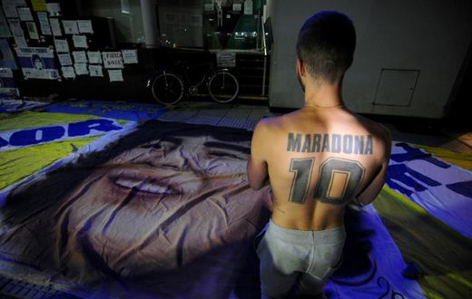 A supporter of Diego Maradona, kneels outside the private clinic where Argentine former football star underwent brain surgery for a blood clot