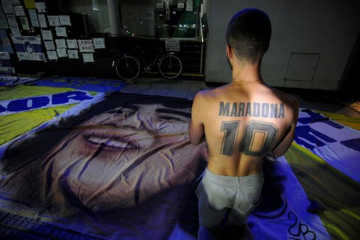 A supporter of Diego Maradona, kneels outside the private clinic where Argentine former football star underwent brain surgery for a blood clot