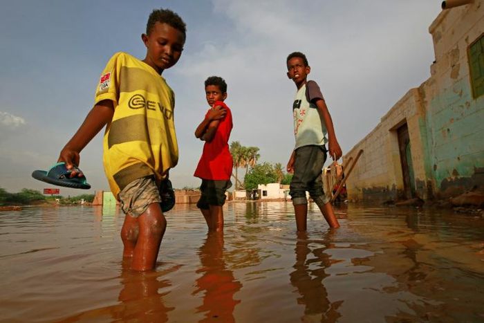 Sudanese boys make their way through a flooded street in the capital's twin city of Omdurman