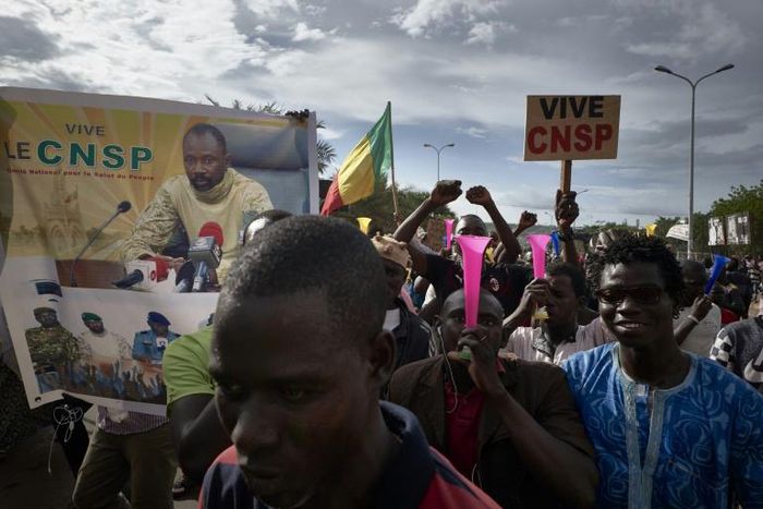 Supporters of the junta, which calls itself the CNSP (National Committee for the Salvation of the People), walk past a banner depicting its leader Assimi Goita in a rally in Bamako on Wednesday