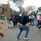 Protesters run from a stun grenade fired by police outside the Zimbabwean Embassy in South Africa's Pretoria