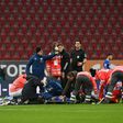 Medics tend to Schalke striker Mark Uth after a frightening clash of heads with Augsburg defender Felix Uduokhai