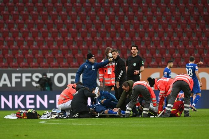 Medics tend to Schalke striker Mark Uth after a frightening clash of heads with Augsburg defender Felix Uduokhai
